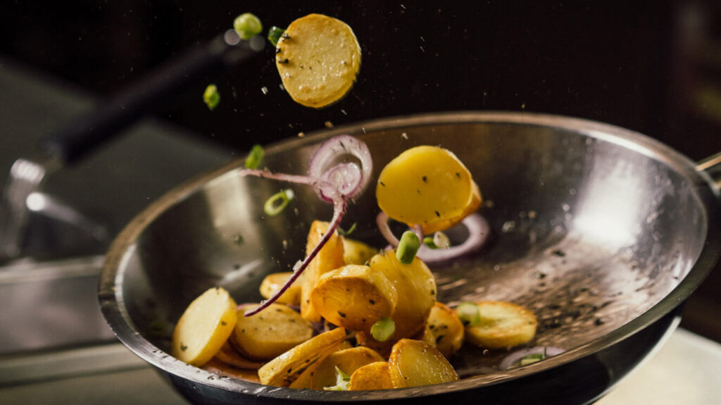 Aufnahme von Bratkartoffeln, die in der Pfanne geschwenkt werden.